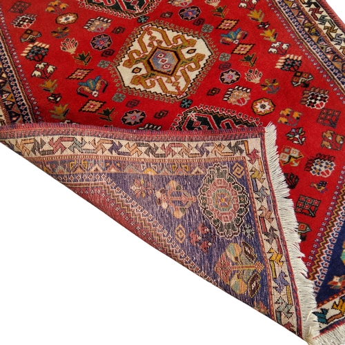 700 - An Oriental Qashgai rug, vivid tones of red and blue, three central guls, 159cm x 109cm