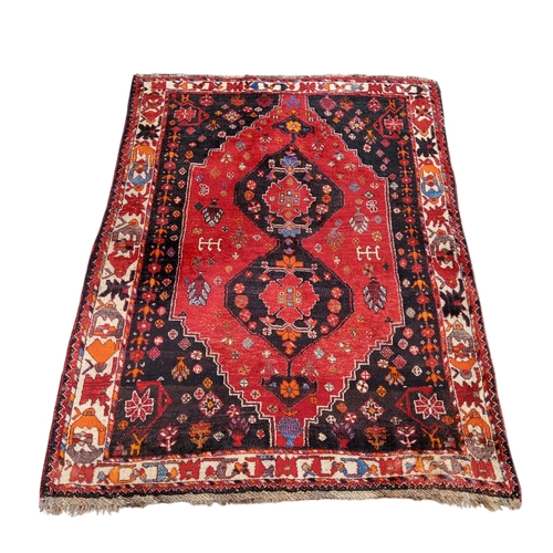 705 - An Oriental Qashgai rug in vivid tones of red, black and orange, 184cm x 130cm