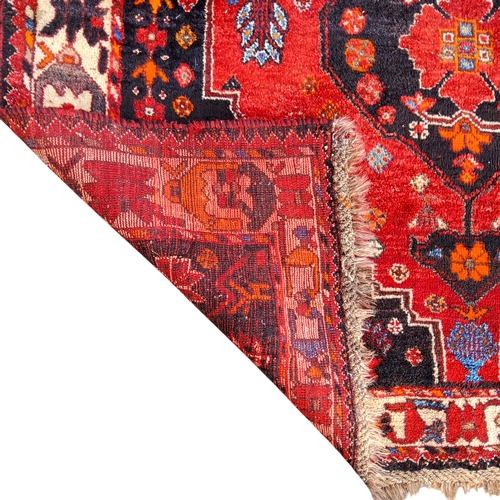 705 - An Oriental Qashgai rug in vivid tones of red, black and orange, 184cm x 130cm