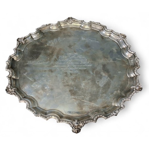 14 - A large silver shaped circular salver, scroll feet, the field inscribed Presented to W H Gilbert Esq... 