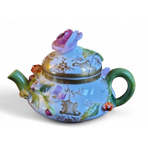 344 - A Minton miniature teapot and cover,  encrusted with leaves and flowers, crossed swords in blue