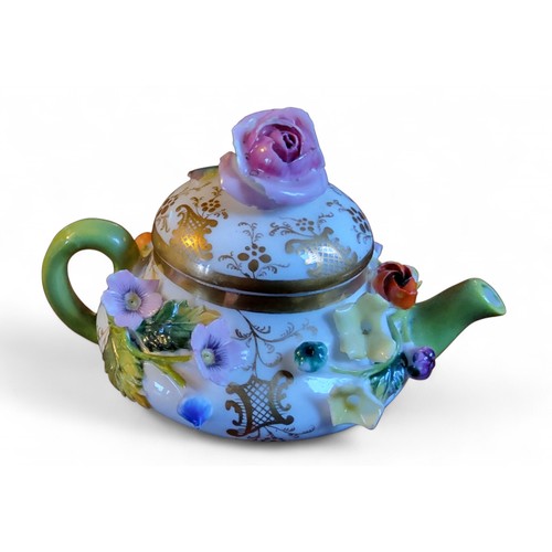 344 - A Minton miniature teapot and cover,  encrusted with leaves and flowers, crossed swords in blue