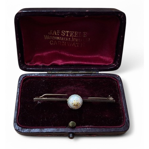 37 - An unusual 9ct gold and opal bar brooch, centrally mounted with an orb made up of two opal cabochons... 