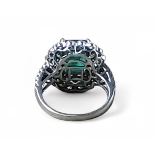242 - An 18ct white gold, emerald and diamond ring, the central four claw set emerald cut emerald, 7.5 x 1... 