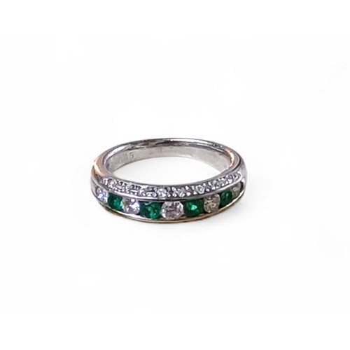 244 - A platinum and part 18ct white gold, emerald and diamond half eternity ring, channel set with four r... 