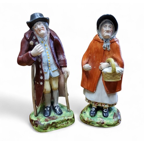 20 - A pair of Staffordshire Pearlware figures, Old Age, modelled with two elderly figures, she with a ba... 