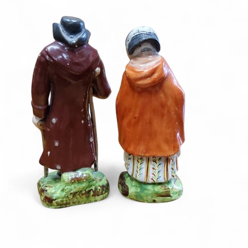 20 - A pair of Staffordshire Pearlware figures, Old Age, modelled with two elderly figures, she with a ba... 