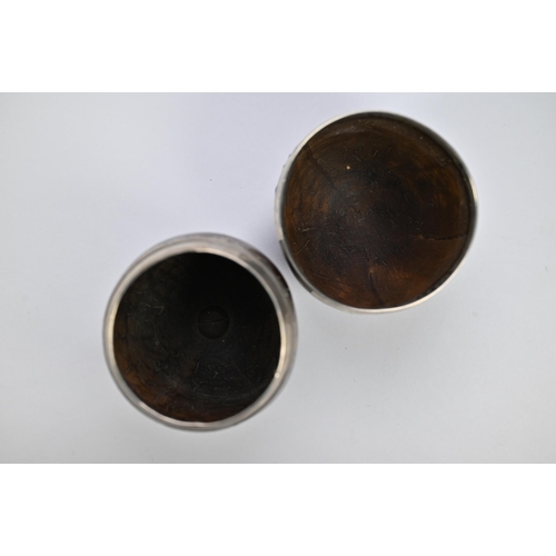 28 - Two antique coconut cups with white metal rims, one with moulded foot-rim, 12cm high, the other with... 