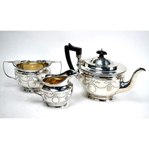 61 - An Edwardian Adam Revival silver three-piece tea service engraved with ribbons and garlands, James D... 