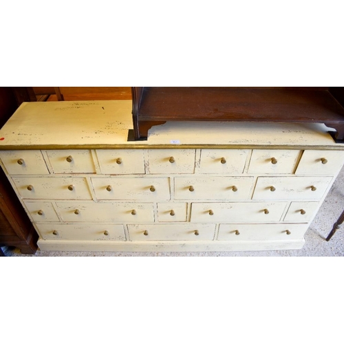 266 - A cream painted hardwood chest of nineteen irregularly arranged drawers on a plinth base, 158 cm w x... 