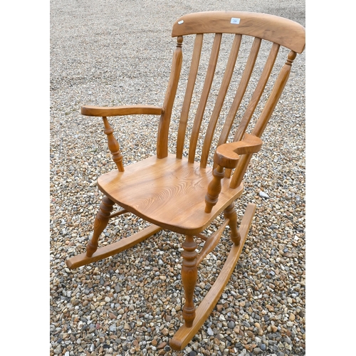 298 - A golden elm slat back rocking chair with shaped seat and turned legs