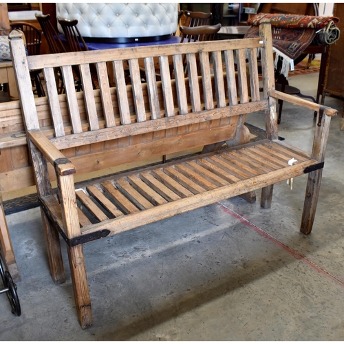 390A - A rustic stained pine hall bench with iron braces/mounts, slatted back and seat, 132 cm wide