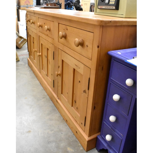 414 - A large pine dresser base with three drawers over panelled cupboards, all with turned handles, 185 c... 