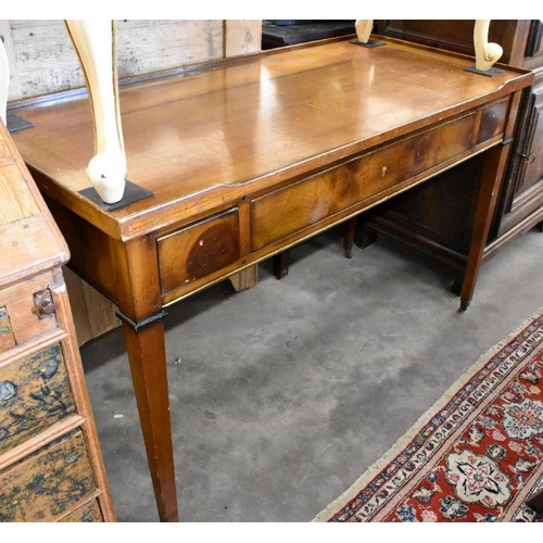 435 - An Empire style fruit wood three drawer writing table on tapering square supports with brass casters... 