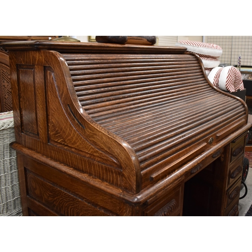 477 - A large late 19th century roll-top oak desk with sliding tambour panel enclosing fitted interior ove... 