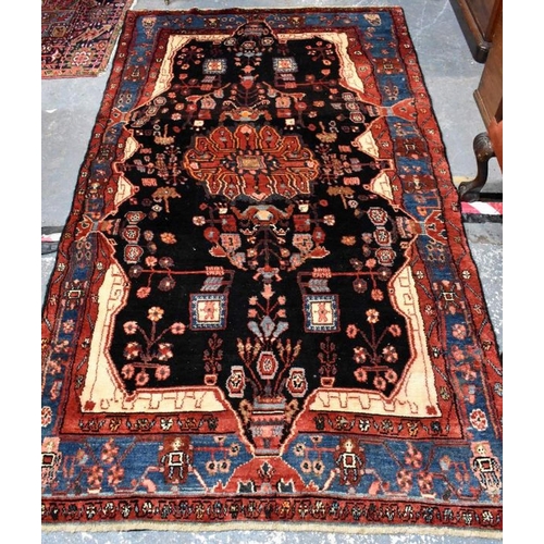 507 - A Persian Nahawand carpet, centred by a large ink black medallion within multi-coloured borders, 245... 