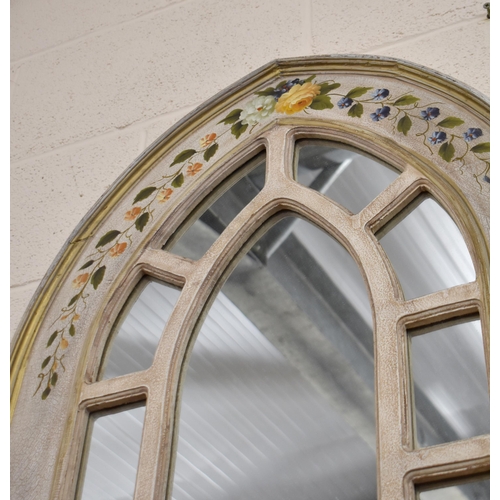 560 - A Gothic arch shaped wall mirror with cream painted frame and polychrome floral sprays, 111 x 61 cm,... 