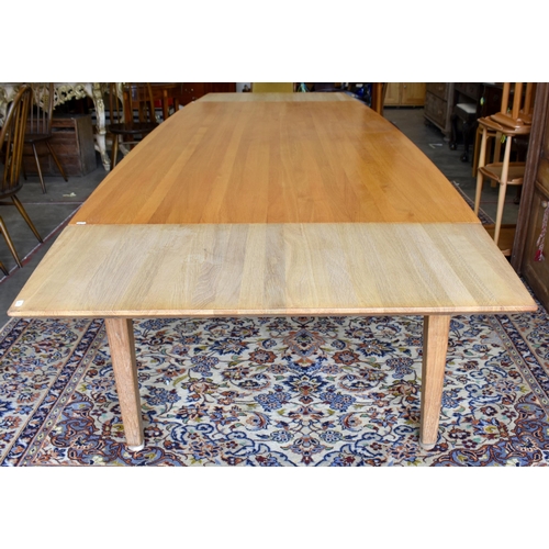 579 - A modern stained light oak dining table with shaped rectangular draw-leaf top raised on tapering squ... 