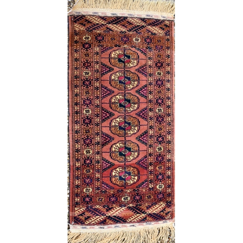 613 - A Persian Bokhara rug, gul design on brick ground, multi borders, 105 cm x 51 cm, to/w two Baluch na... 