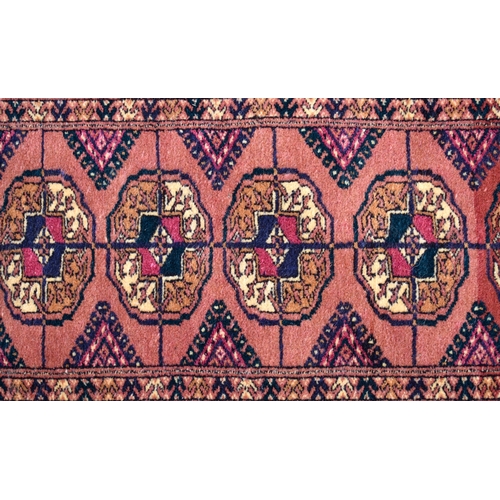 613 - A Persian Bokhara rug, gul design on brick ground, multi borders, 105 cm x 51 cm, to/w two Baluch na... 