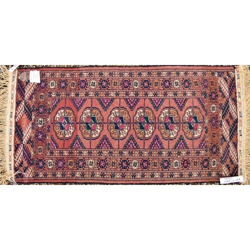 613 - A Persian Bokhara rug, gul design on brick ground, multi borders, 105 cm x 51 cm, to/w two Baluch na... 