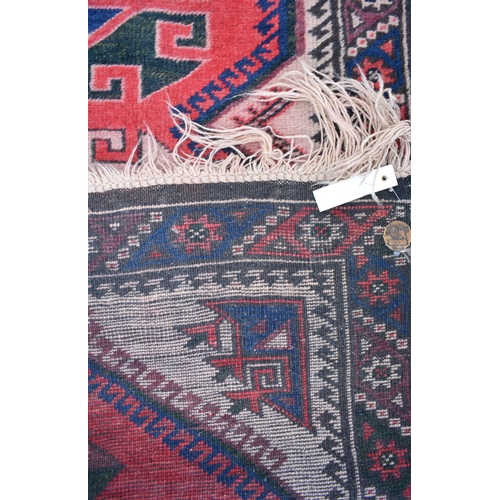 627 - A Caucasian geometric design red ground runner with brown border, 310 x 80 cm