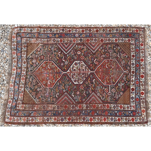 630 - A Caucasian brown ground rug with flora and fauna design around three pole linked central medallions... 