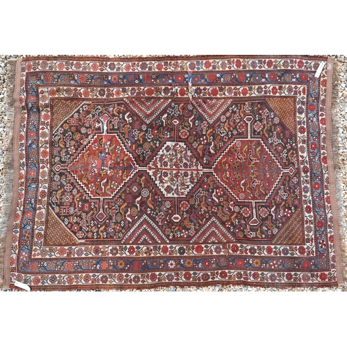 630 - A Caucasian brown ground rug with flora and fauna design around three pole linked central medallions... 