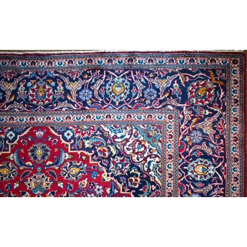 632 - A Persian Kashan carpet, the red ground with floral vines centred by a blue diamond medallion, 305 c... 