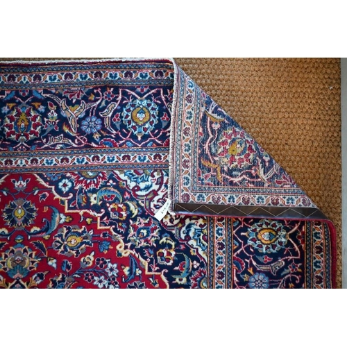 632 - A Persian Kashan carpet, the red ground with floral vines centred by a blue diamond medallion, 305 c... 