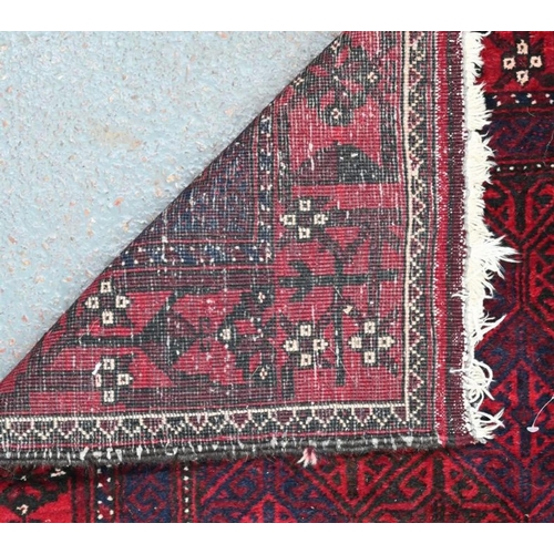 633 - A contemporary Belouch rug, the repeating geometric design on dark red ground, 190 cm x 95 cm