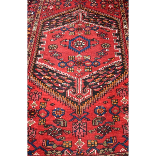 635 - A Persian Shiraz rug with dark medallion on red ground, 207 x 133 cm