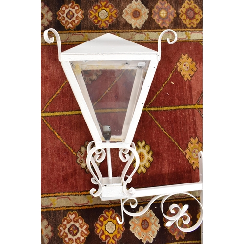 639 - An old painted four-glass lantern of square tapering form mounted on scrolling wrought iron wall bra... 