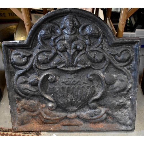 648 - A heavy arched iron fire-back cast with lower flower filled twin-handled un, 54 cm wide x 52 cm high