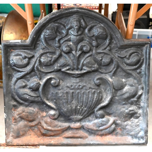 648 - A heavy arched iron fire-back cast with lower flower filled twin-handled un, 54 cm wide x 52 cm high