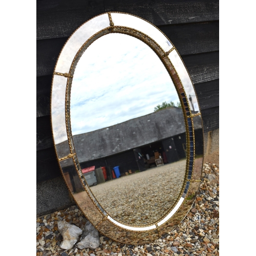 649 - Venetian style oval wall mirror with gilt floral embellished gilt metal edging, 105 x 70 cm