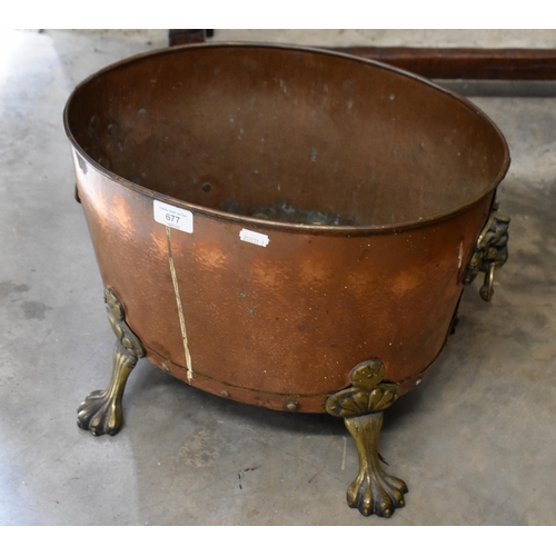 677 - An antique oval copper planter with brass lion mask handles and feet, 42 x 32 cm