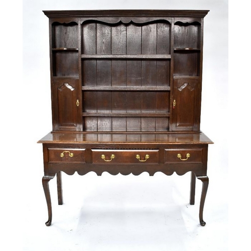 76 - An 18th century style oak high dresser, the upper with an arrangement of shelves and two fielded arc... 