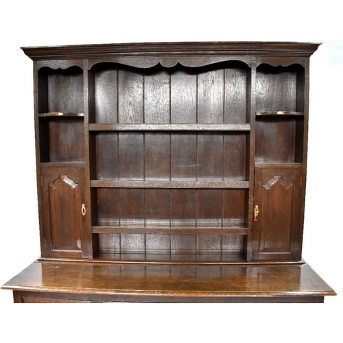 76 - An 18th century style oak high dresser, the upper with an arrangement of shelves and two fielded arc... 