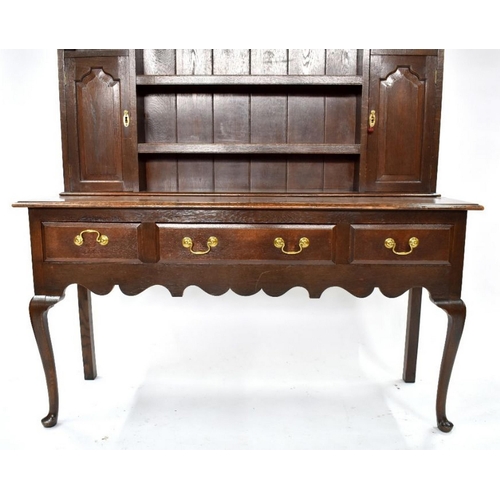 76 - An 18th century style oak high dresser, the upper with an arrangement of shelves and two fielded arc... 