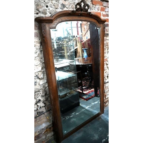 82 - A vintage French oak framed arched top mirror, surmounted by a moulded ribbon bow device, 180 cm x 1... 