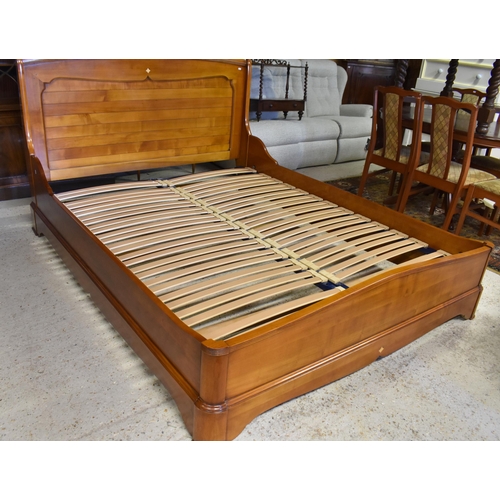 222 - Brigitte Forestier - A cherrywood kingsize sleigh bed with panelled headboard and slatted base on tw... 