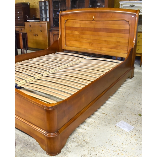 222 - Brigitte Forestier - A cherrywood kingsize sleigh bed with panelled headboard and slatted base on tw... 