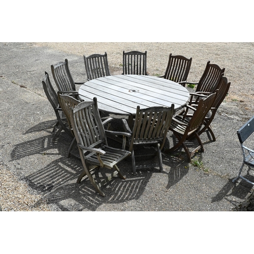 18 - A large weathered teak circular garden dining table 180 cm diameter x 74 cm high to/w seven weathere... 