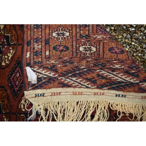 507 - A contemporary Turkoman design rug, the repeating gul design on rust-red ground, 270 cm x 83 cm