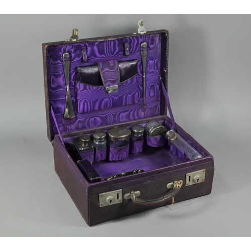 108 - A purple leather small suitcase, the watered silk and Morocco leather lining fitted with five silver... 