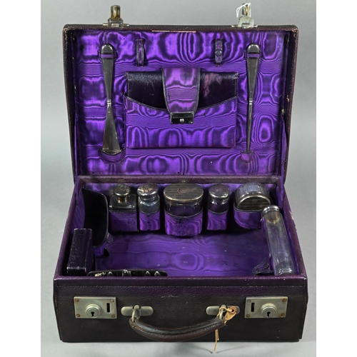 108 - A purple leather small suitcase, the watered silk and Morocco leather lining fitted with five silver... 