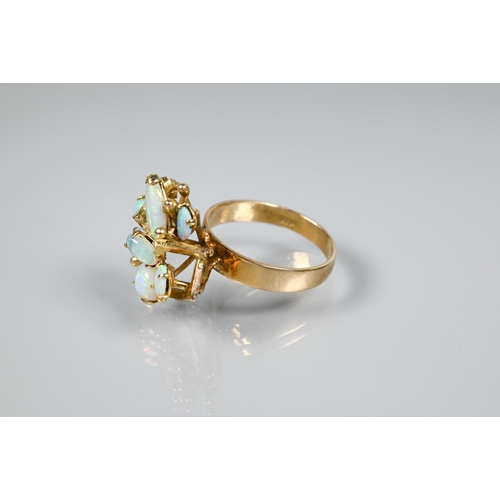 151 - An opal cluster ring, the stylised angular open work setting with seven oval opals, on wide flat sha... 