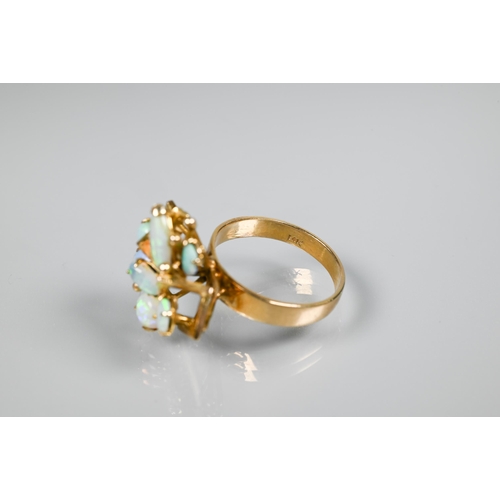 151 - An opal cluster ring, the stylised angular open work setting with seven oval opals, on wide flat sha... 