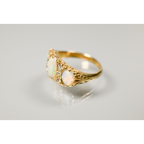 186 - An antique three-stone opal and diamond ring, the graduated opals with three small diamonds between,... 